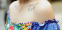 A close-up of a woman's shoulder tattoo and colorful off-shoulder dress.